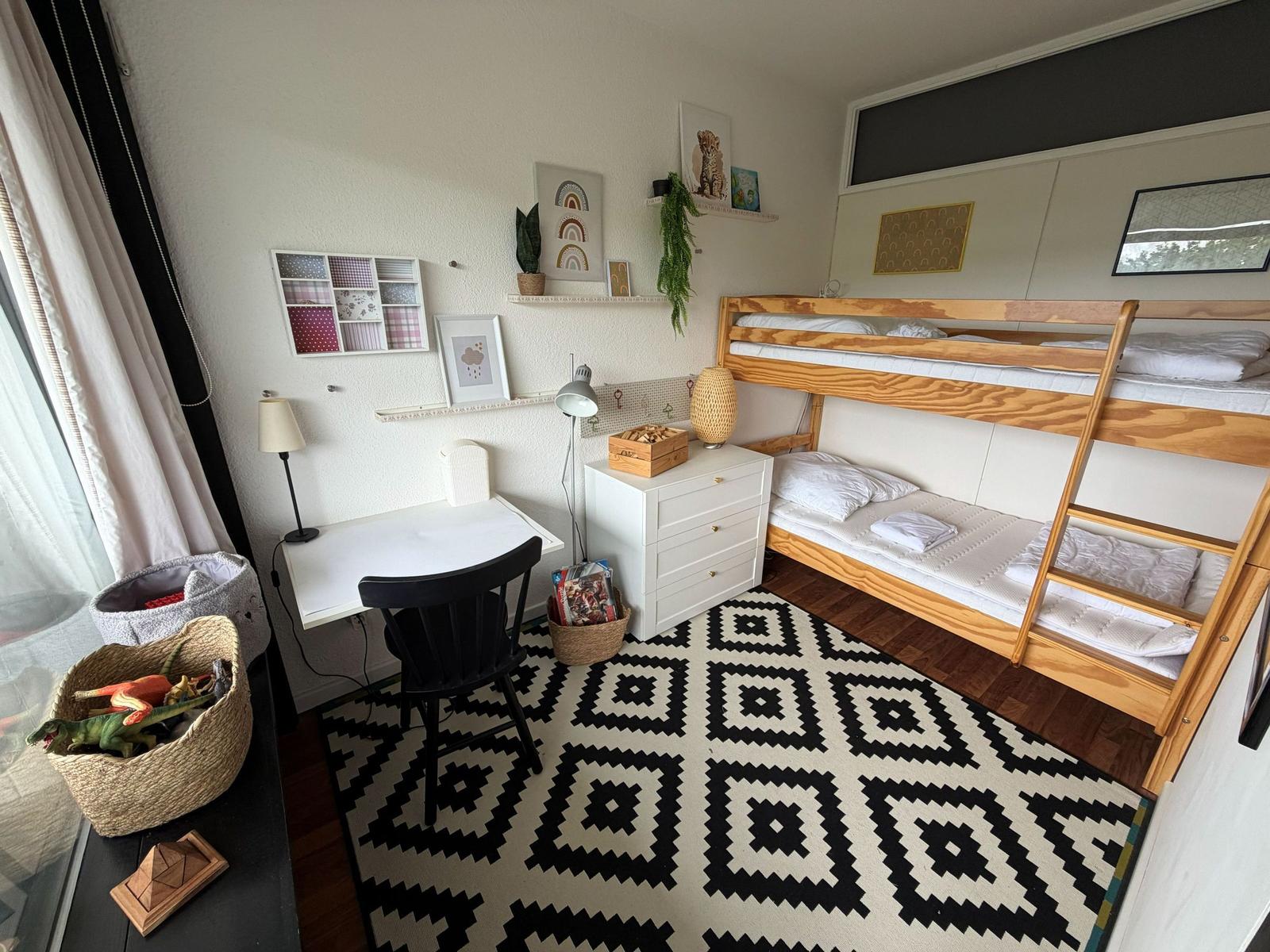 Ein Schlafzimmer mit Doppelbett, Schreibtisch und Regal mit Dekoration.