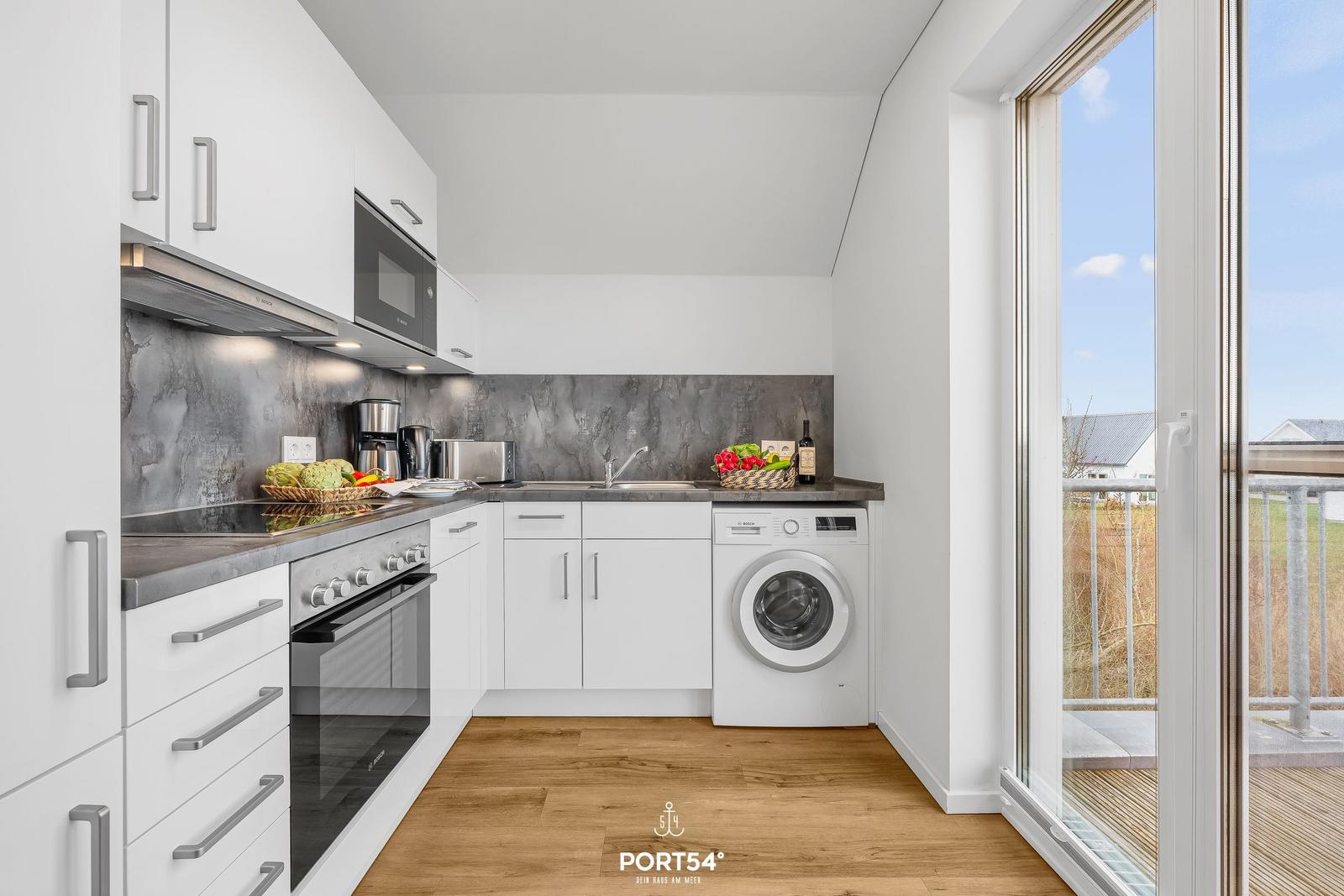 Moderne Küche mit Waschmaschine und Blick auf Balkon