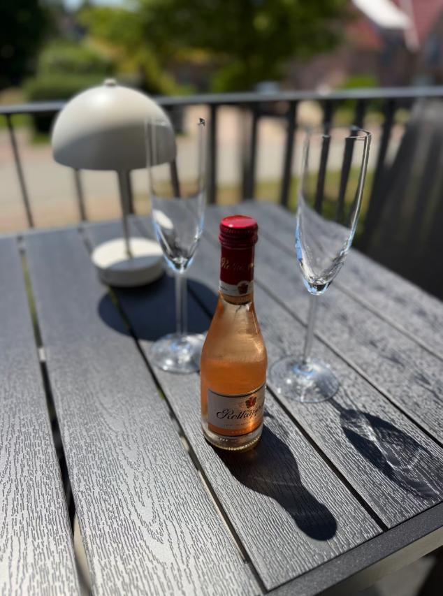 Auf dem Balkon steht ein Tisch mit einer Flasche Rosé, zwei Gläsern und einer Lampe.