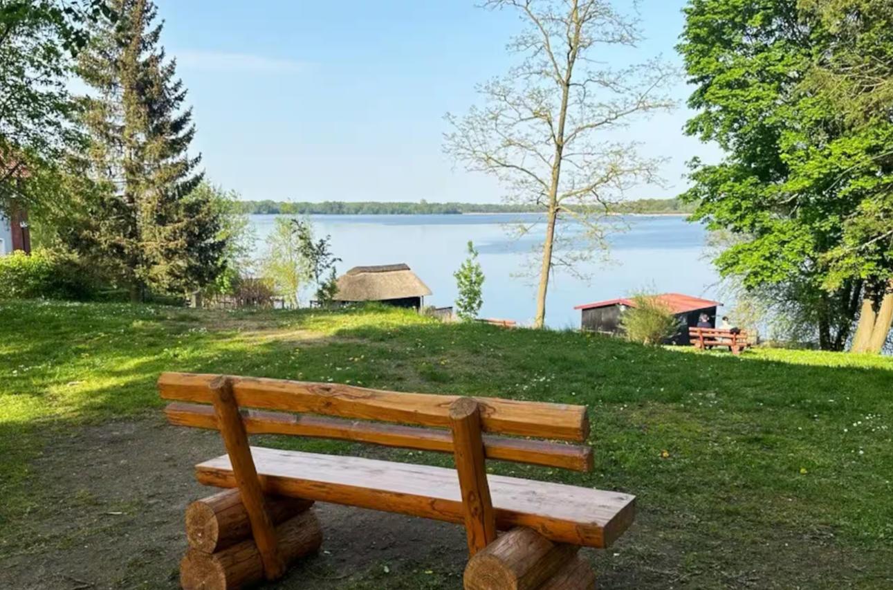 Holzbank am Seeufer mit Blick auf Wasser und Bäume.