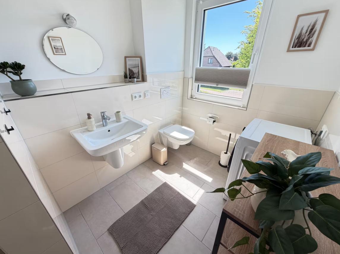 Badezimmer mit Waschbecken, Toilette und Fenster mit Blick nach draußen.