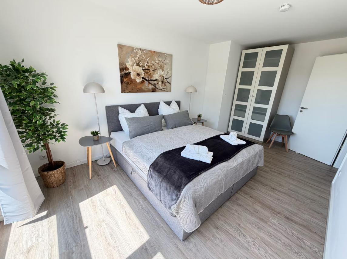 Schlafzimmer mit Bett, Kleiderschrank und Pflanze.