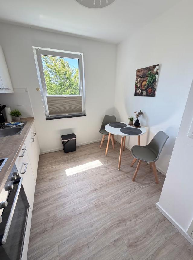 Küche mit Essbereich, Tisch, zwei Stühle und Fenster mit Blick auf Grün.
