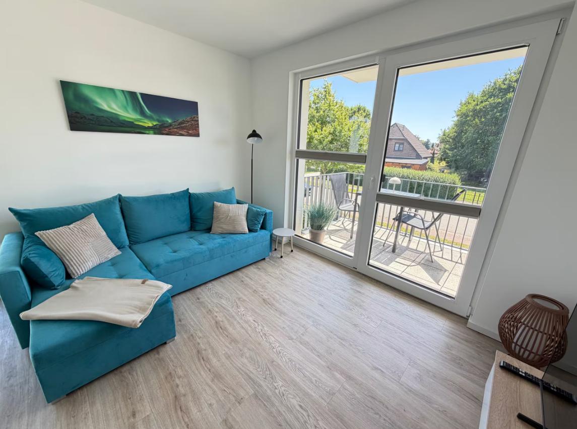 Ein Wohnzimmer mit blauem Sofa, Holzboden und Balkon mit Sitzgelegenheiten.