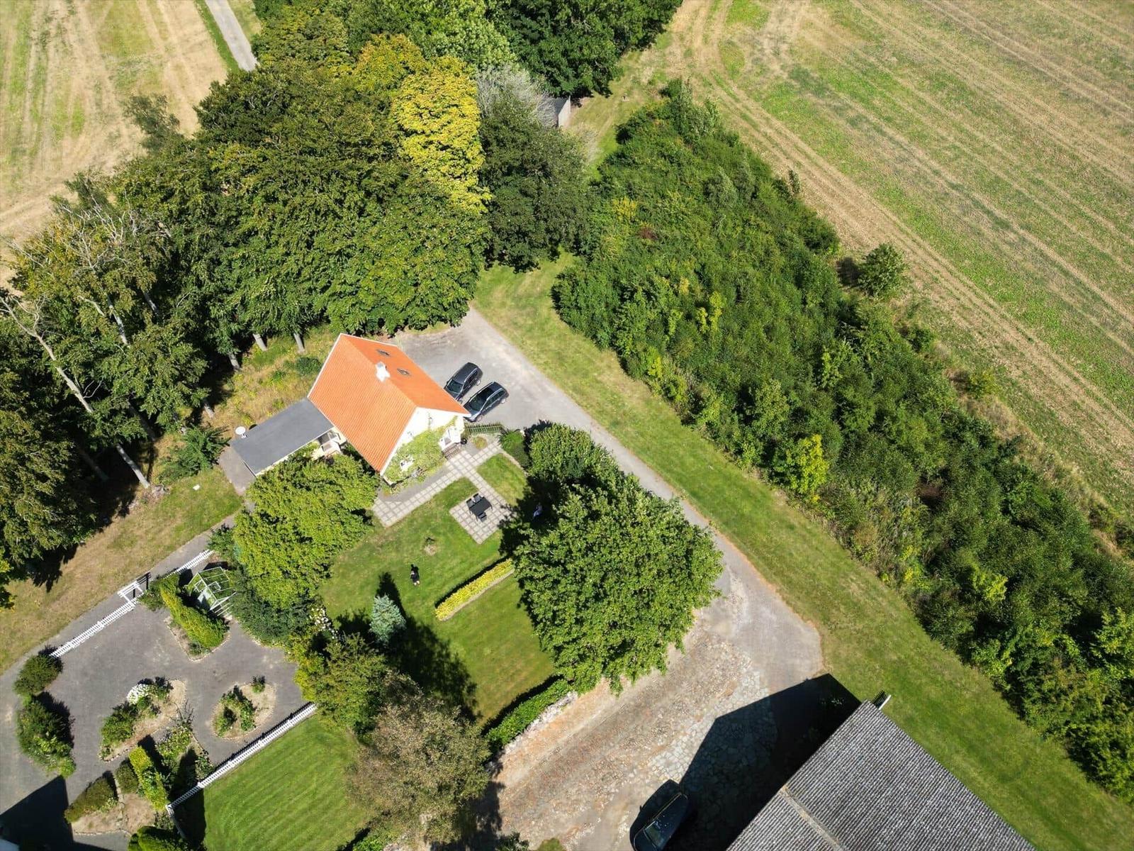 Haus mit rotem Dach, Garten und Parkplatz zwischen Wäldern und Feldern