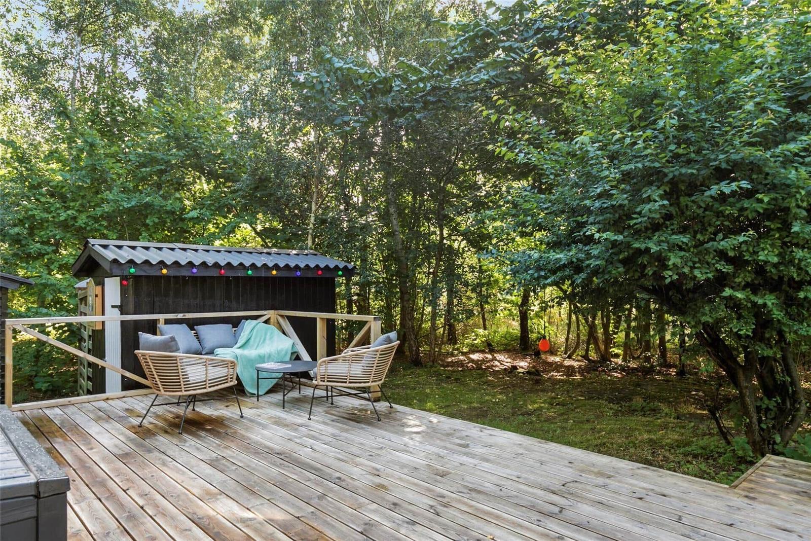 Terrasse mit Sitzgelegenheiten und kleinem Holzhaus im Wald