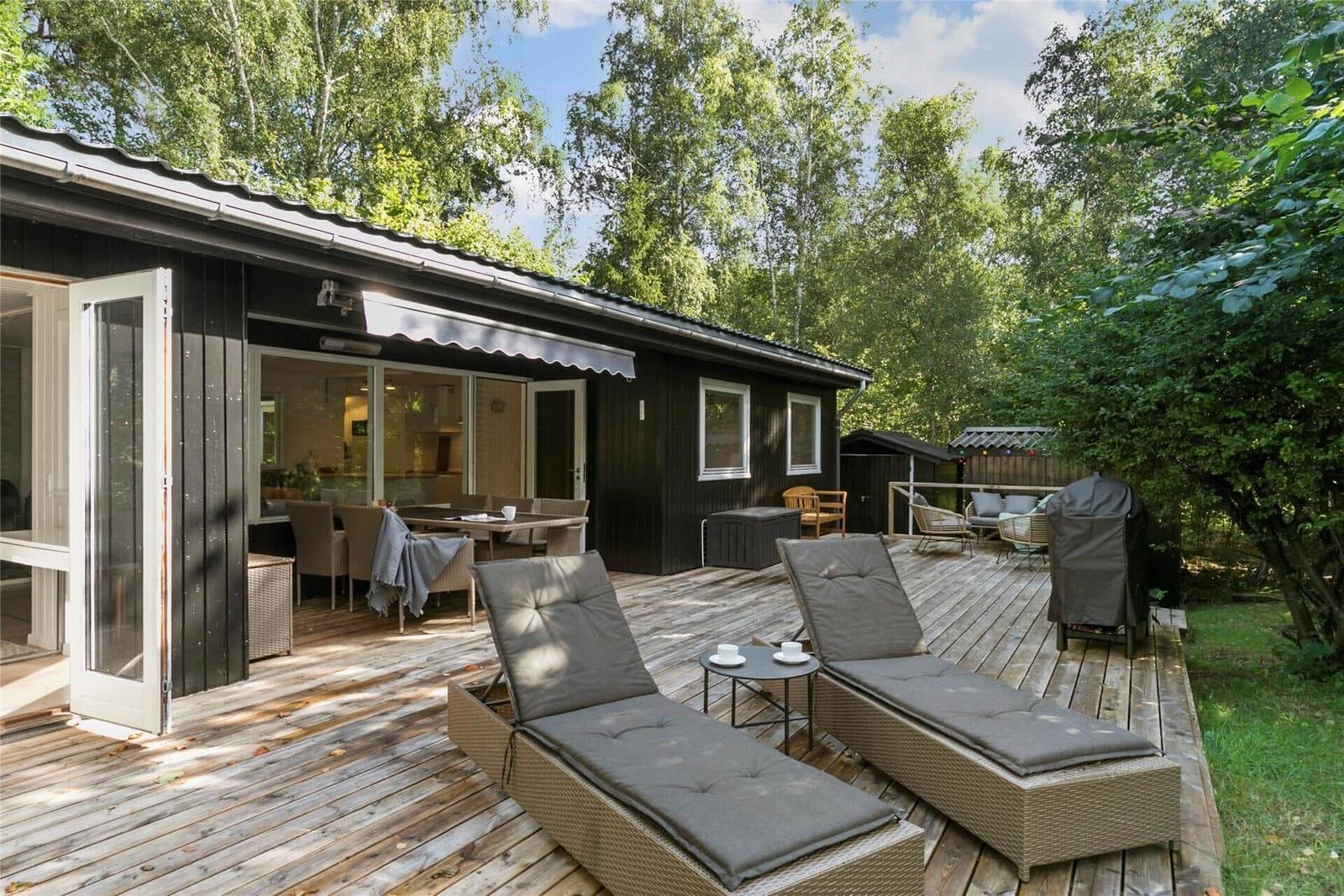 Holzterrasse mit Liegestühlen und Blick in die Küche.