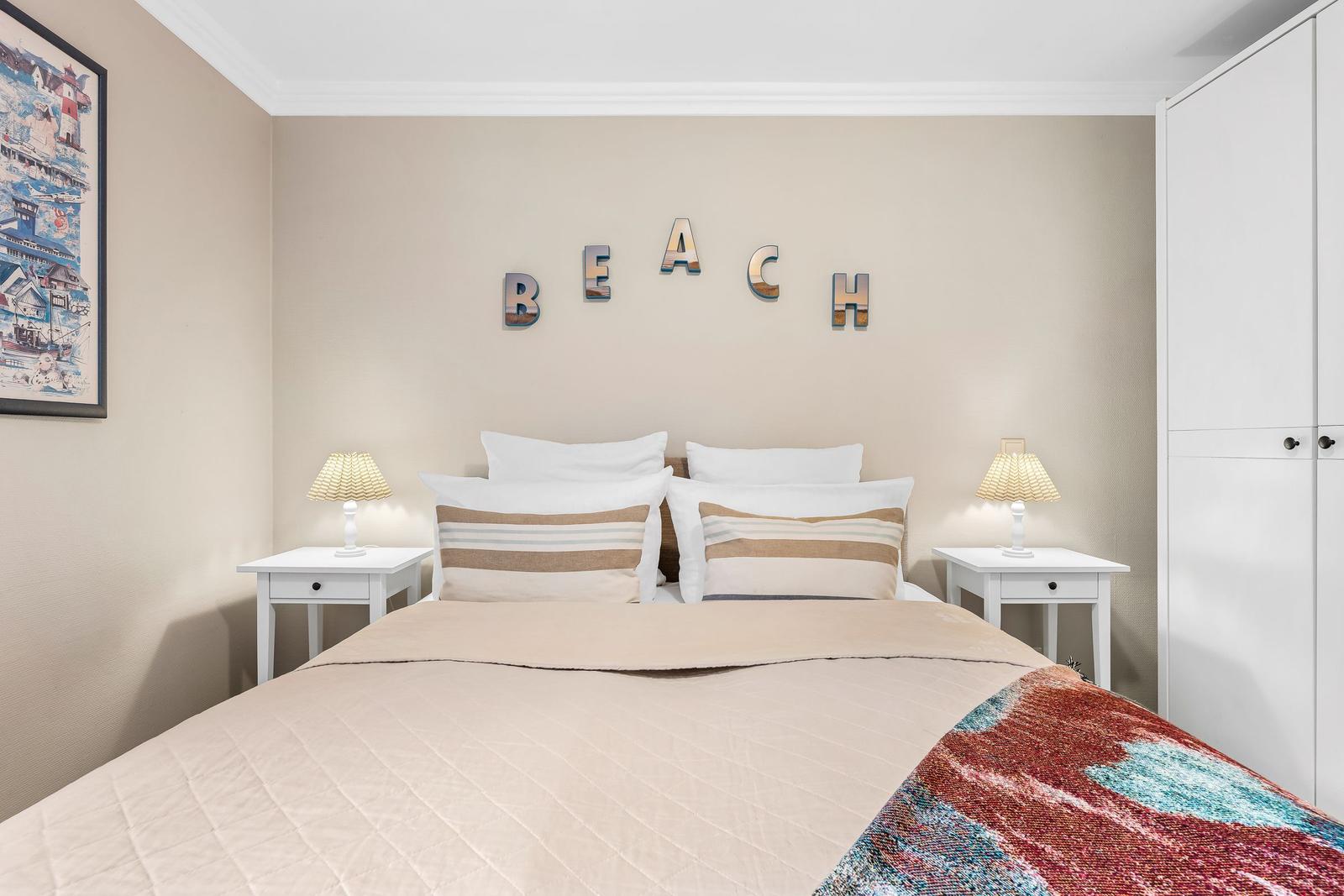 Schlafzimmer mit Bett, Nachttischen und Wanddekoration BEACH.