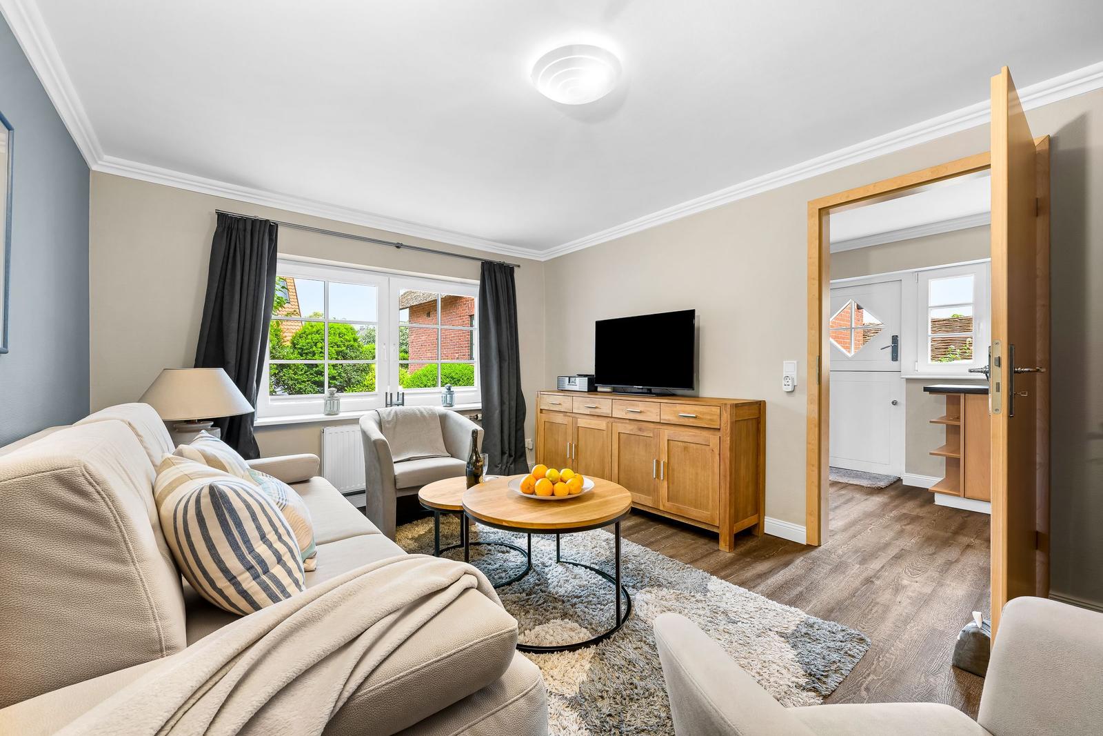 Wohnzimmer mit Sofa, Couchtisch und TV. Durchgang zu Küche und Bad.