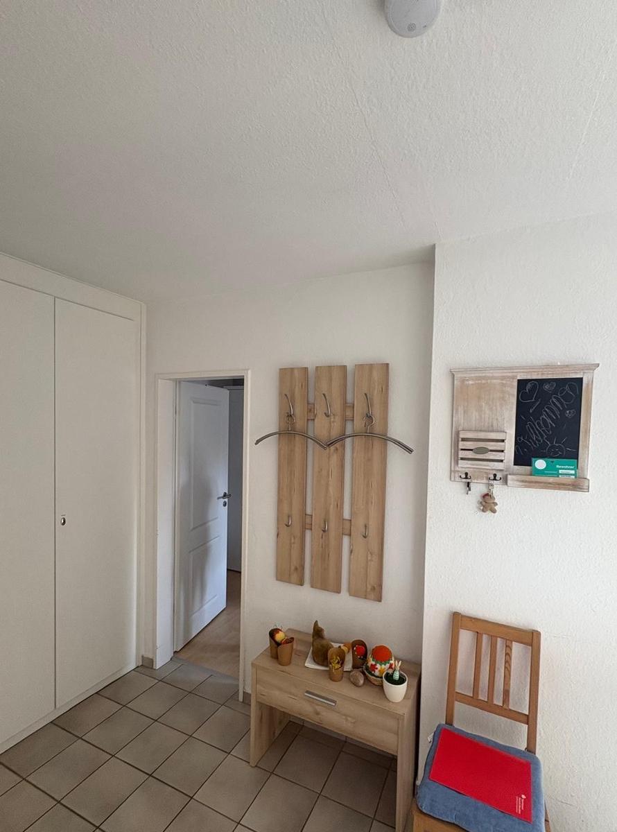 Eingangsbereich mit Kleiderhaken, Tisch und Stuhl. Hintergrund: Tür und Schrank.