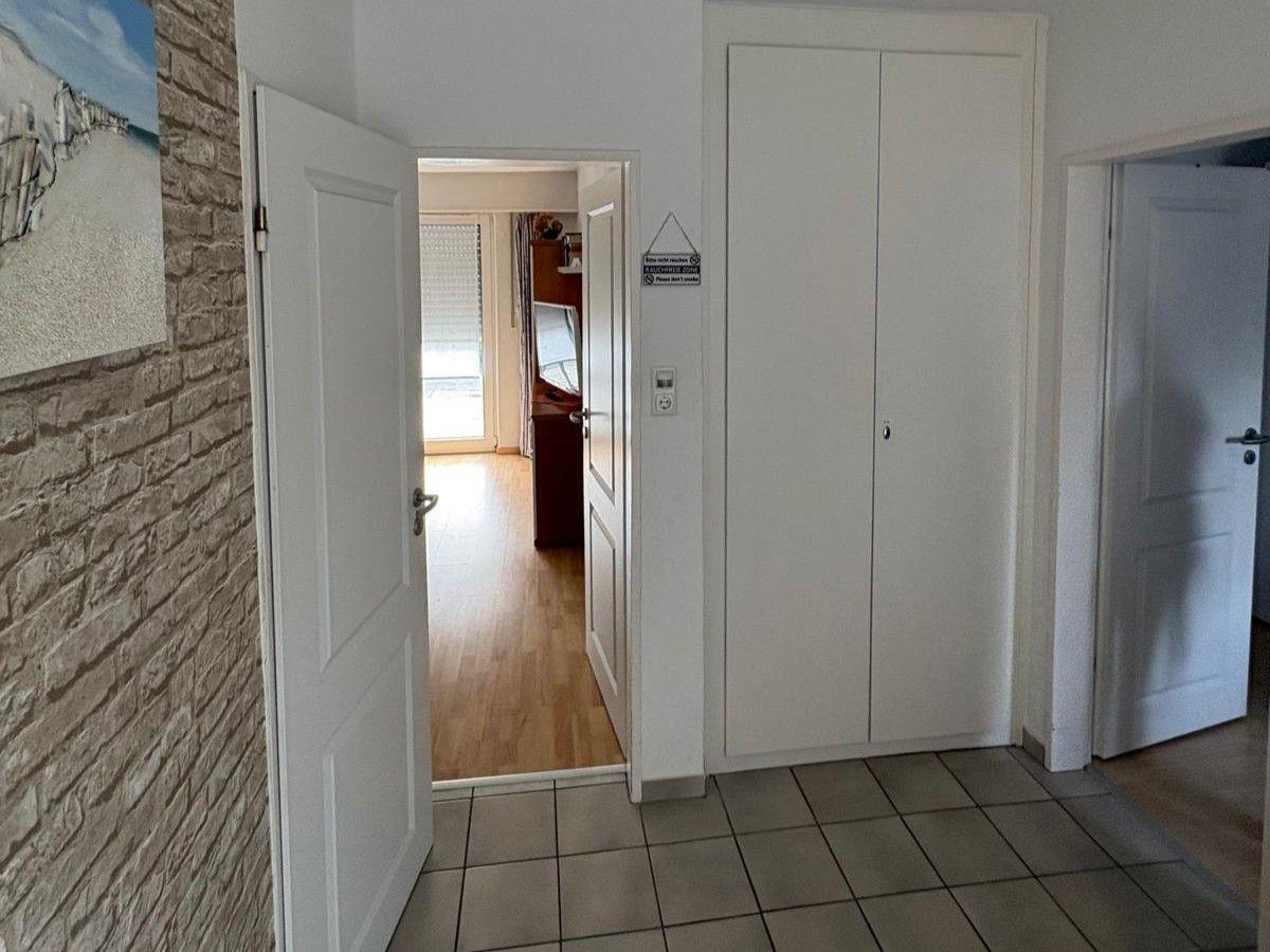 Eingangsbereich mit Fliesenboden und weißen Türen. An der Wand hängt ein Bild.