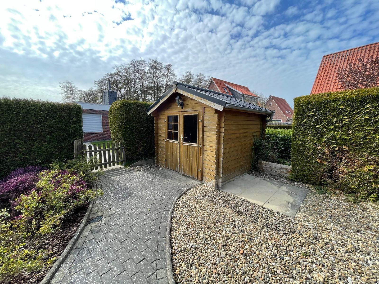 Holzschuppen mit Gartentor und Kiesweg im Garten