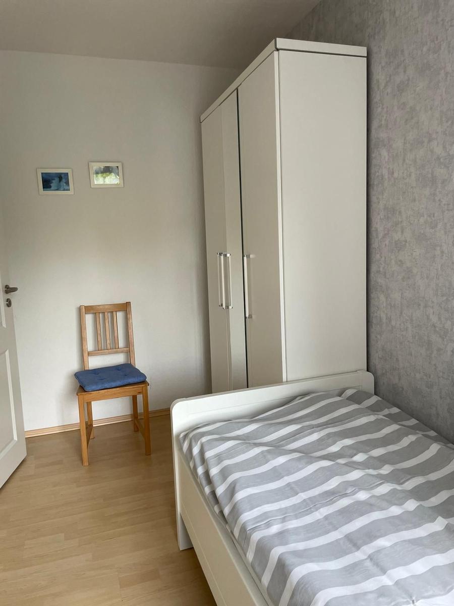 Schlafzimmer mit Bett, Kleiderschrank und Stuhl