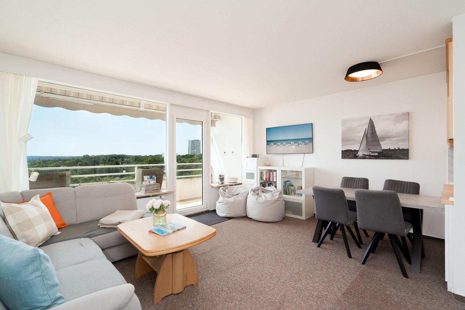 Wohn- und Essbereich mit Balkon, Sofa, Esstisch und Wandbildern.
