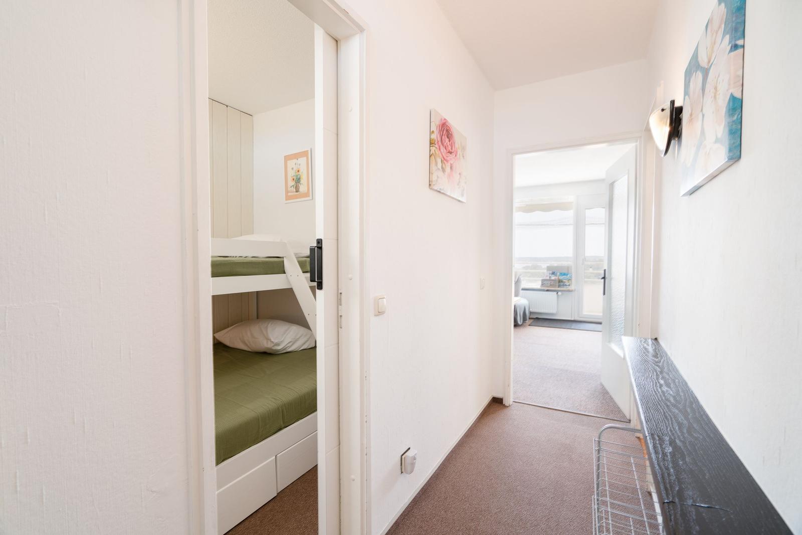 Flur mit Blick in Schlafzimmer mit Doppelstockbett und weiterem Raum mit Fenster.