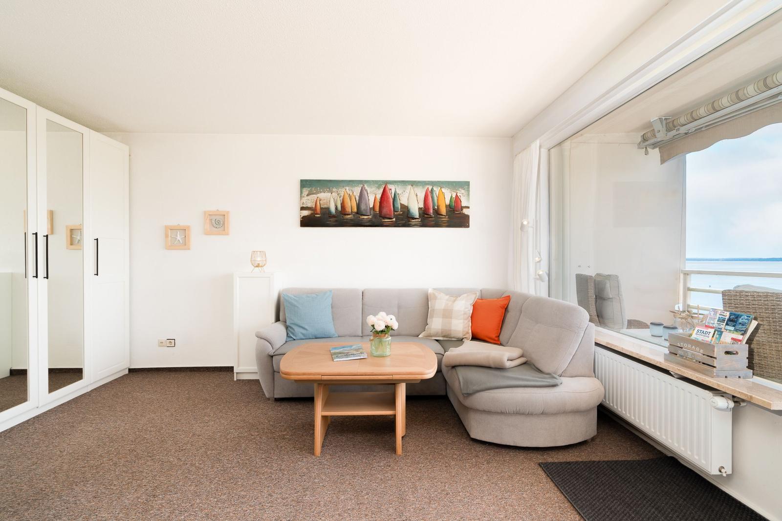 Wohnzimmer mit Sofa, Tisch und Blick aufs Wasser.