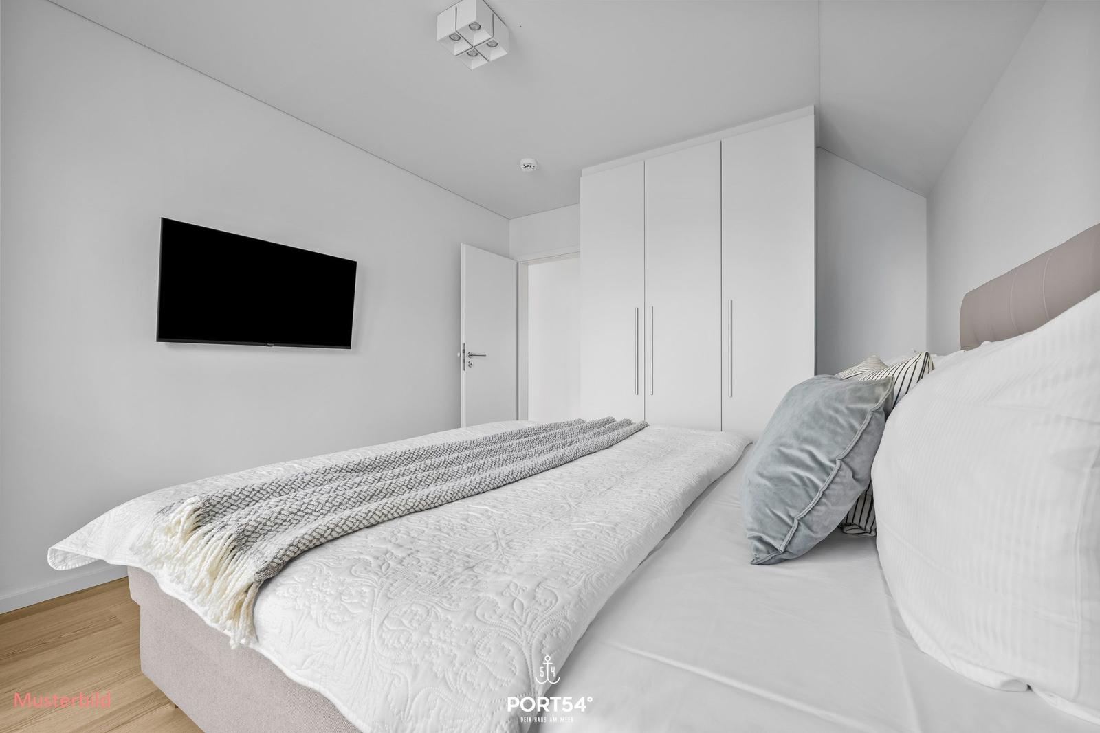 Schlafzimmer mit Bett, Kleiderschrank und Wandfernseher.