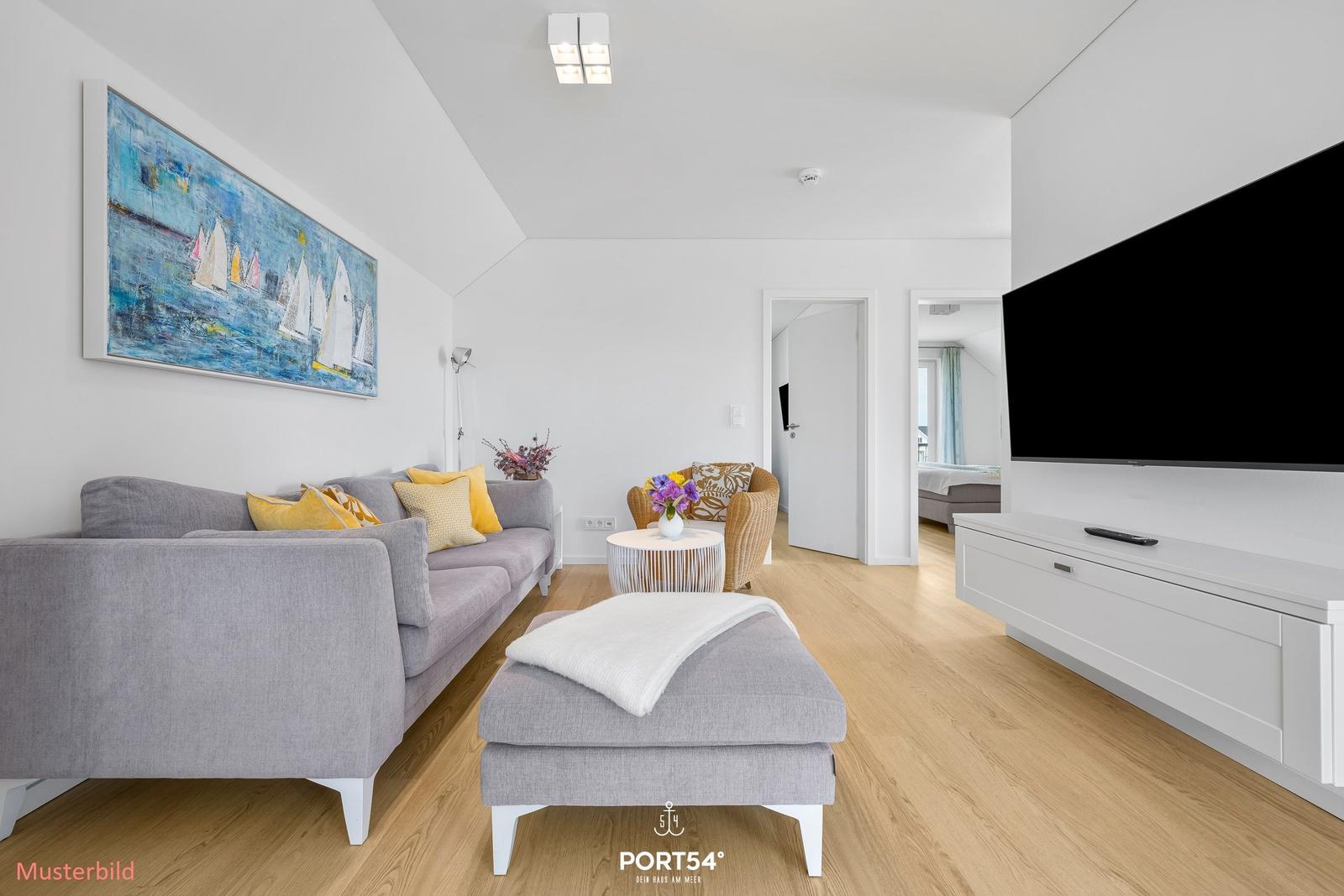 Wohnzimmer mit grauem Sofa, Fernseher und Wandbild mit Segelbooten.