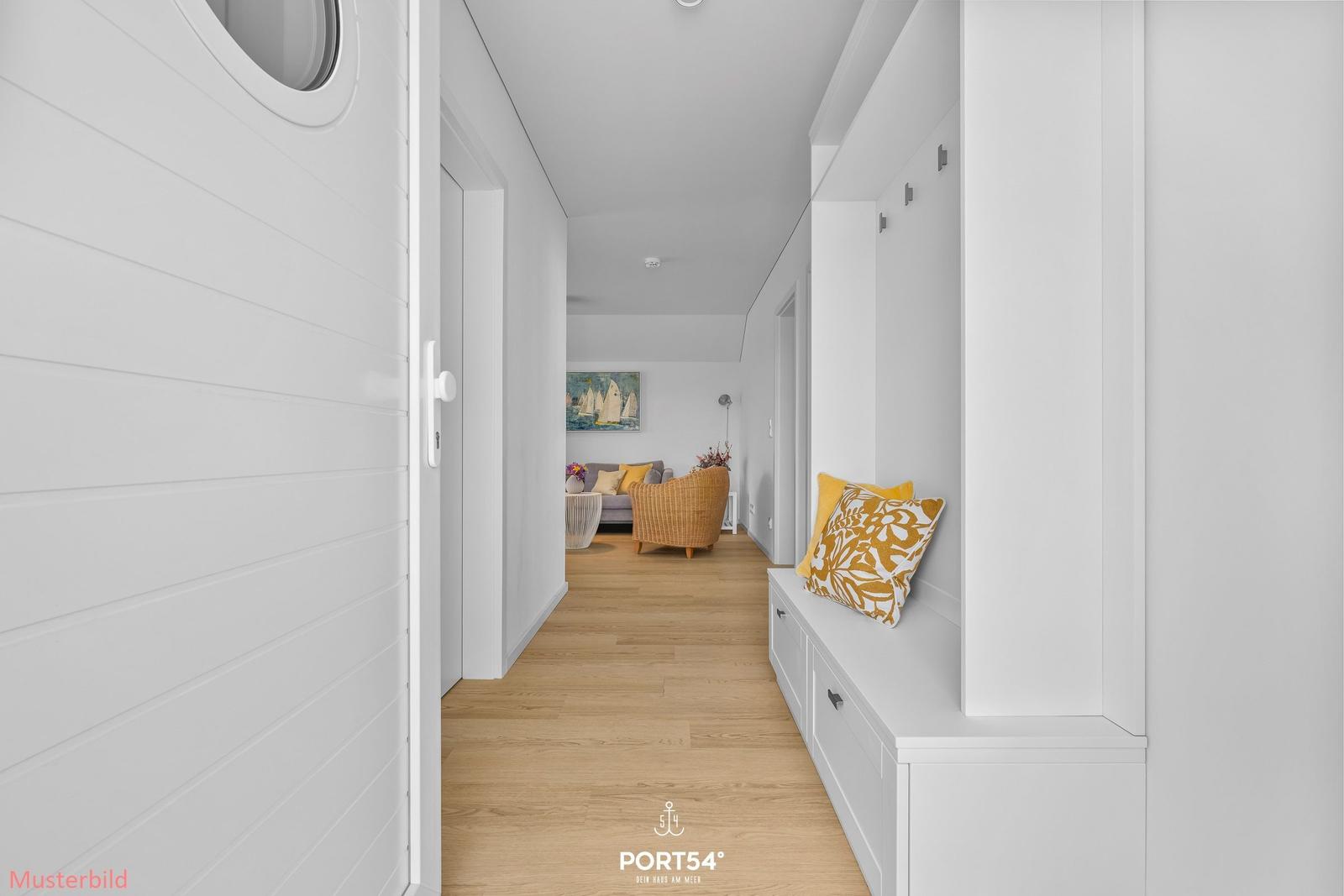 Flur mit weißer Wand und Sitzbank mit Kissen. Holzdielenboden und Blick in Wohnzimmer.