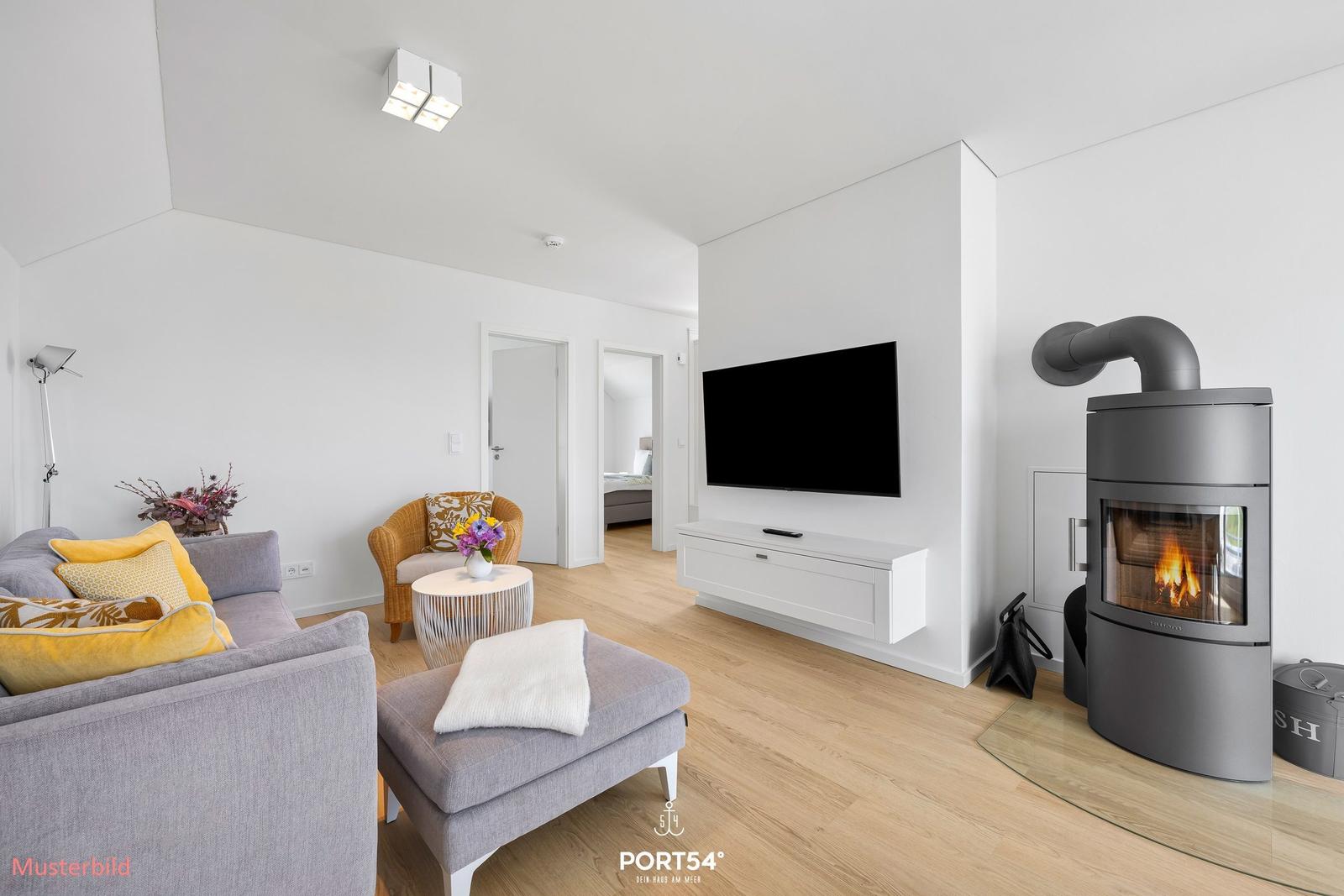 Wohnzimmer mit Sofa, Fernseher und Kaminofen auf Holzfußboden.