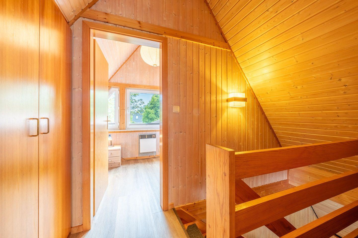Holzgetäfelte Türöffnung zu einem Schlafzimmer mit Fenster und Klimagerät.