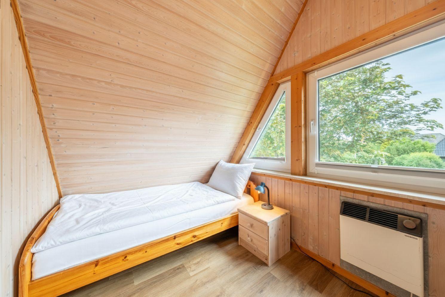 Ein Schlafzimmer mit Holzwand, Bett, Nachttisch und Fenster.