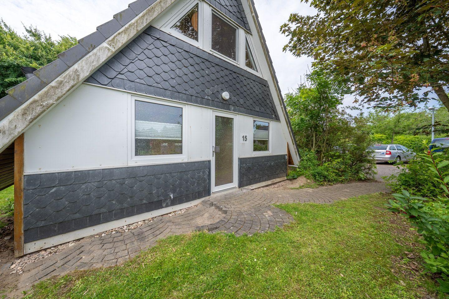 Ein Haus mit grauer Schieferdach und weißer Fassade. Hinterhof mit Gras und Steinweg.