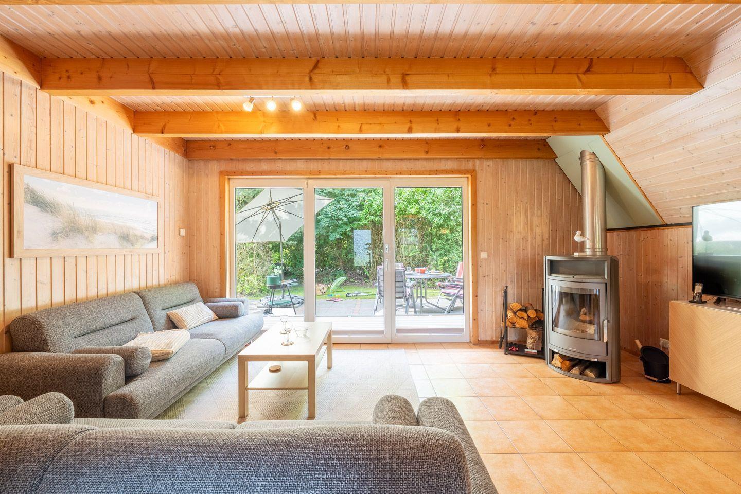 Wohnzimmer mit Holzwand, Sofa, Kamin und Terrassentür.