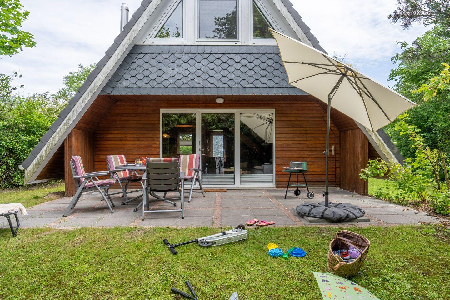 Haus mit Terrasse, Sitzgelegenheiten und Grillplatz im Garten.