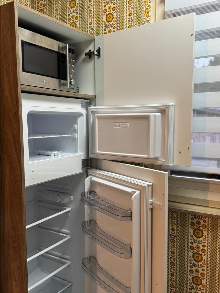 Kühlschrank mit Mikrowelle und Fenster im Hintergrund