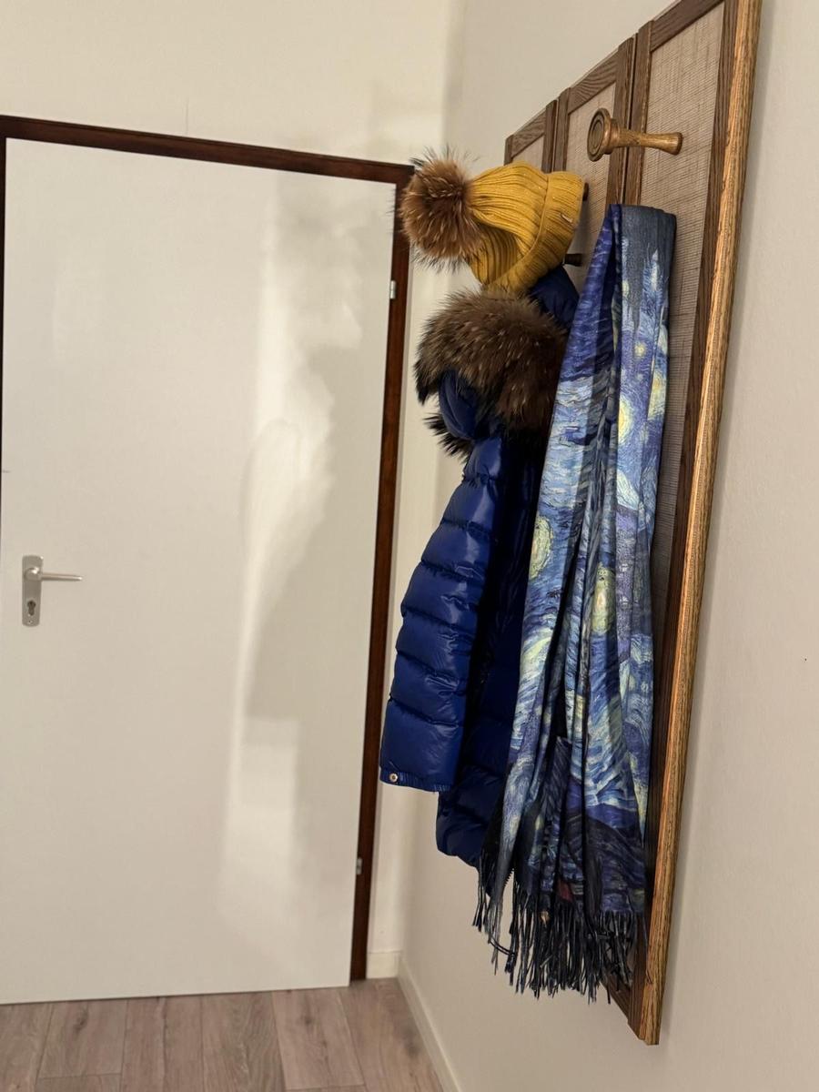 An der Wand hängt ein blauer Mantel, eine Mütze und ein Schal mit Sternennacht-Muster.