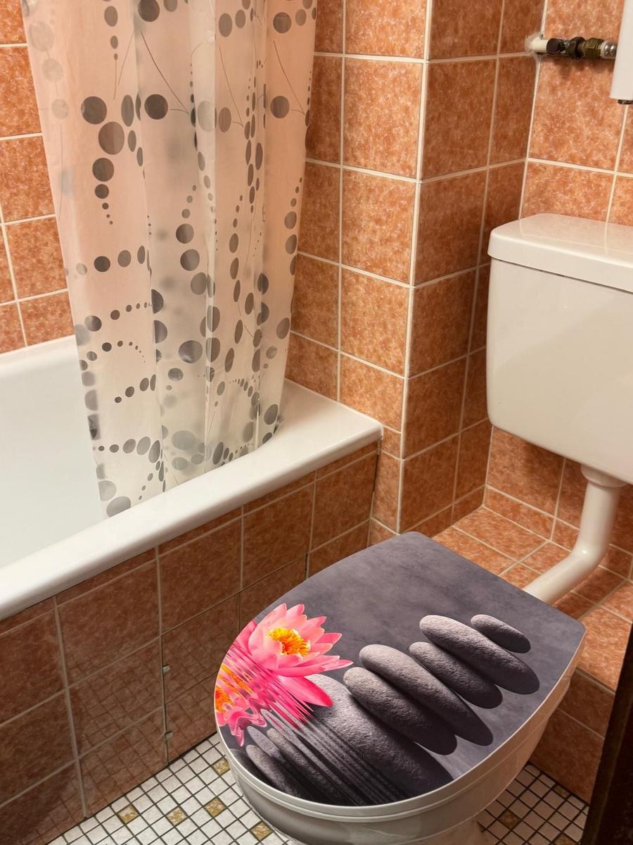 Badezimmer mit Badewanne, Toilette und Duschvorhang mit Punktmuster.