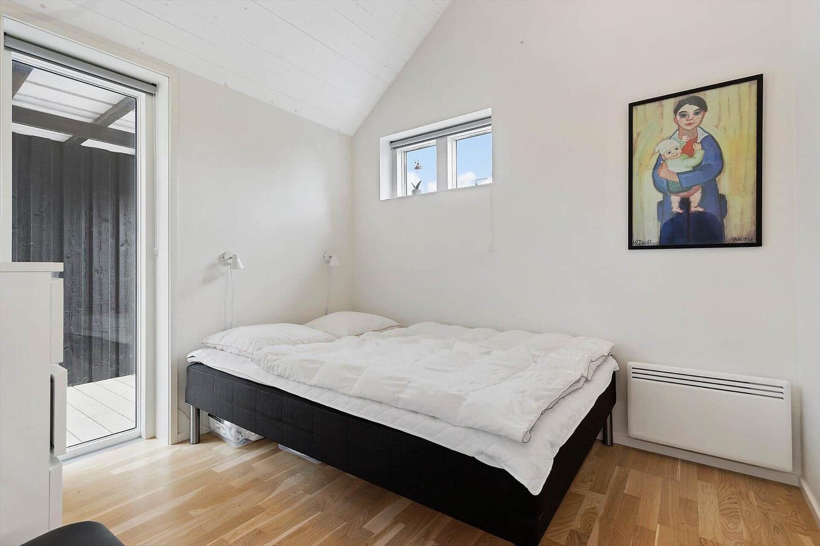 Schlafzimmer mit Bett, Fenster und Wandbild.