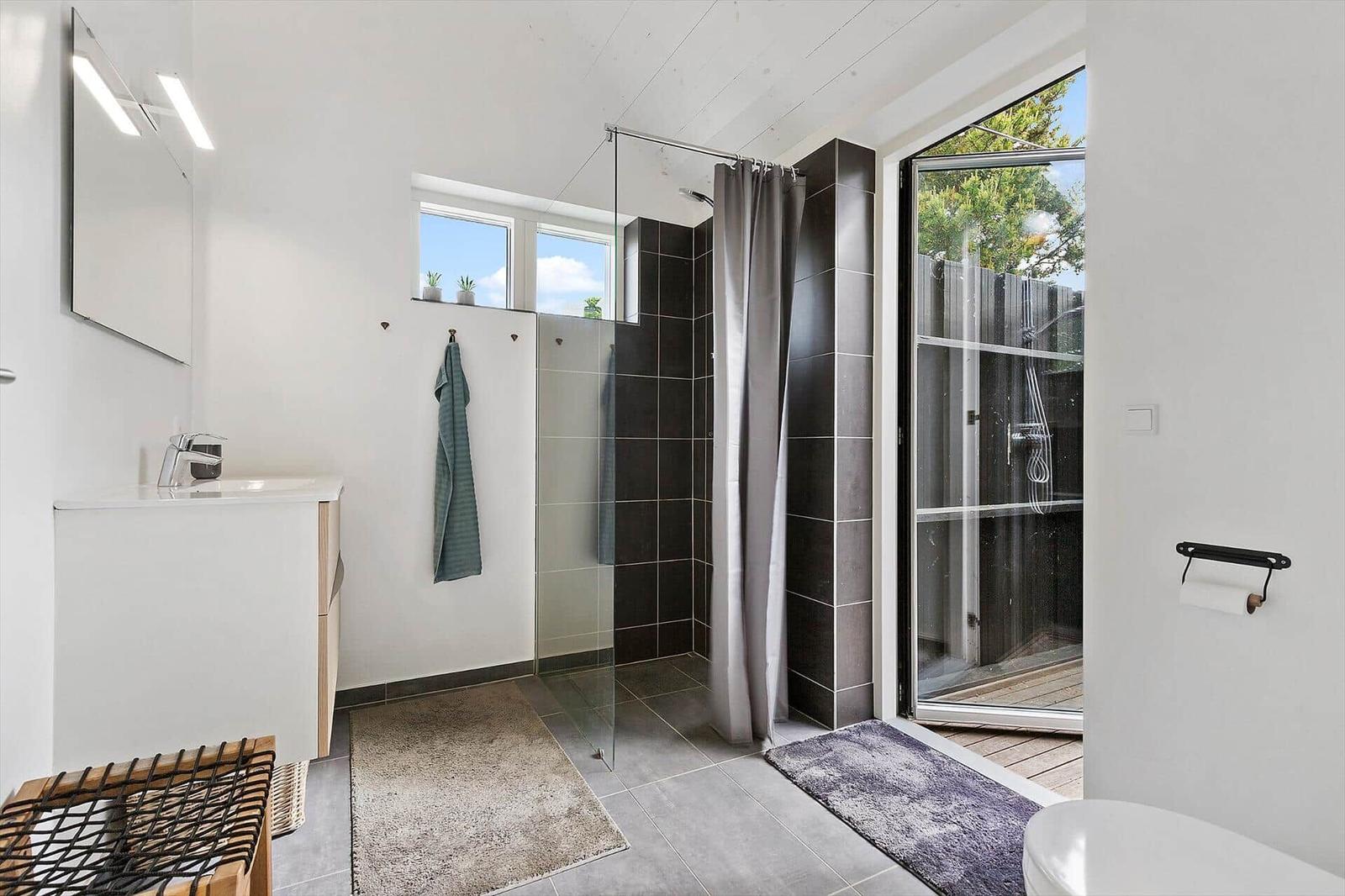 Badezimmer mit Dusche, Waschbecken und Blick auf den Garten.