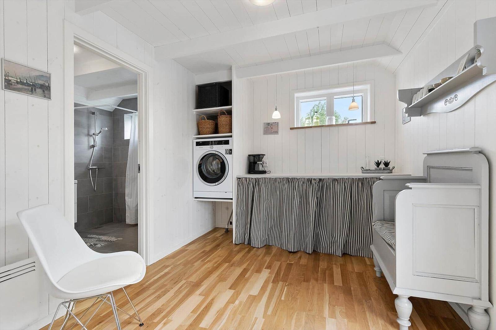 Wohnraum mit Waschmaschine, Fenster und Bett. Badezimmer im Hintergrund.