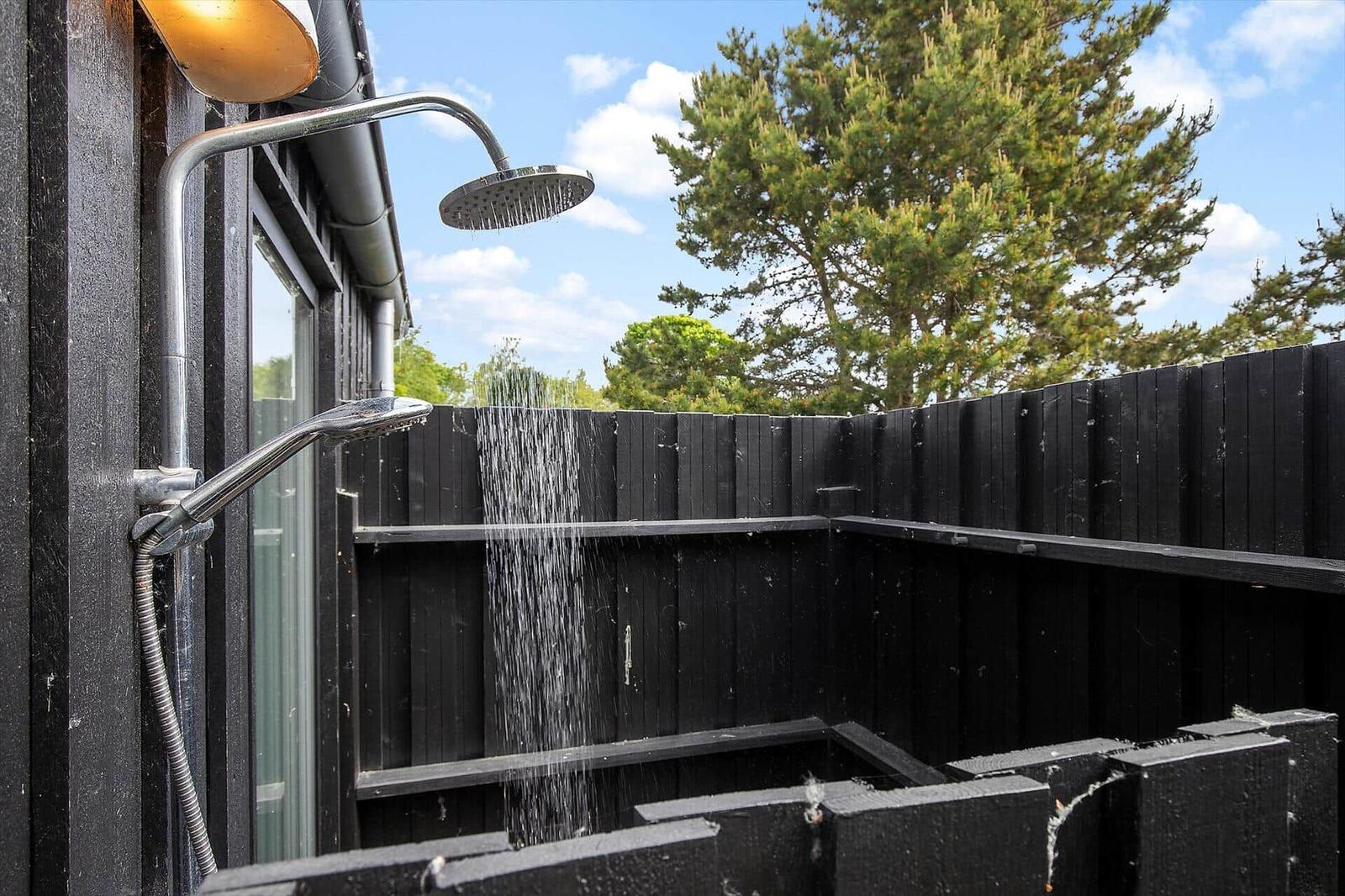 Außen-Dusche mit Regenrinnenabfluss und schwarzen Holzwänden im Garten