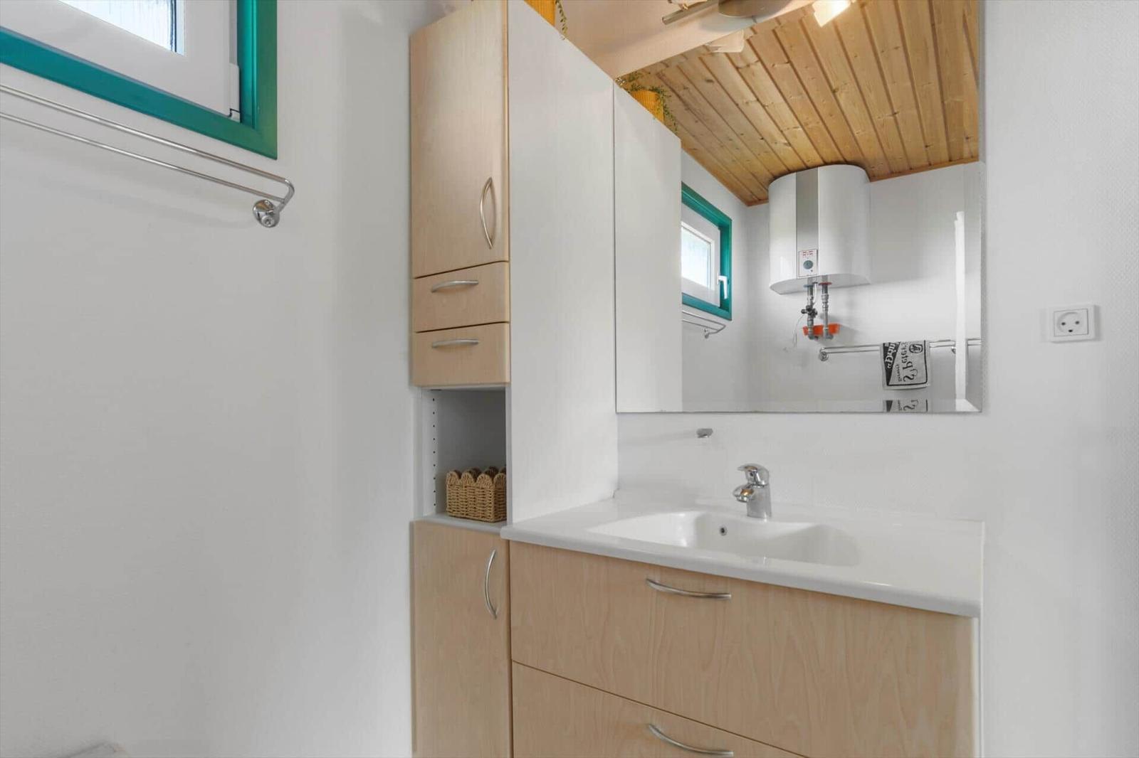Badezimmer mit Waschbecken, Spiegelschrank und Holzdecke