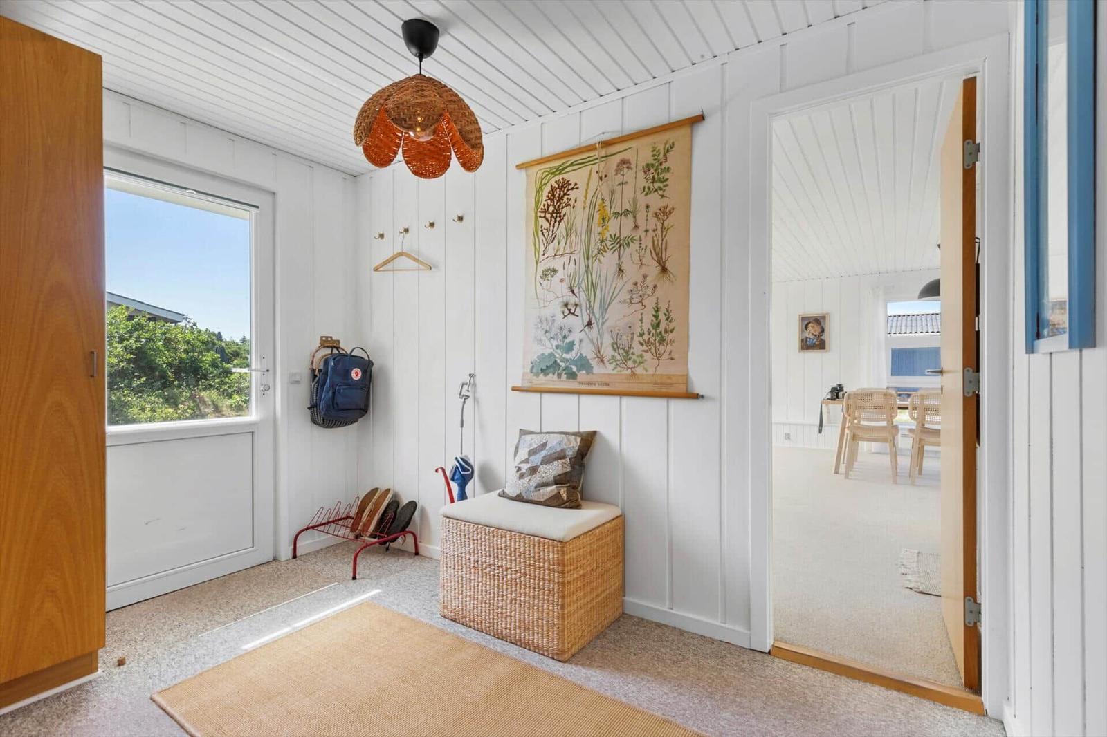 Eingangsbereich mit Wandbild, Sitzkissen und Blick ins Wohnzimmer.