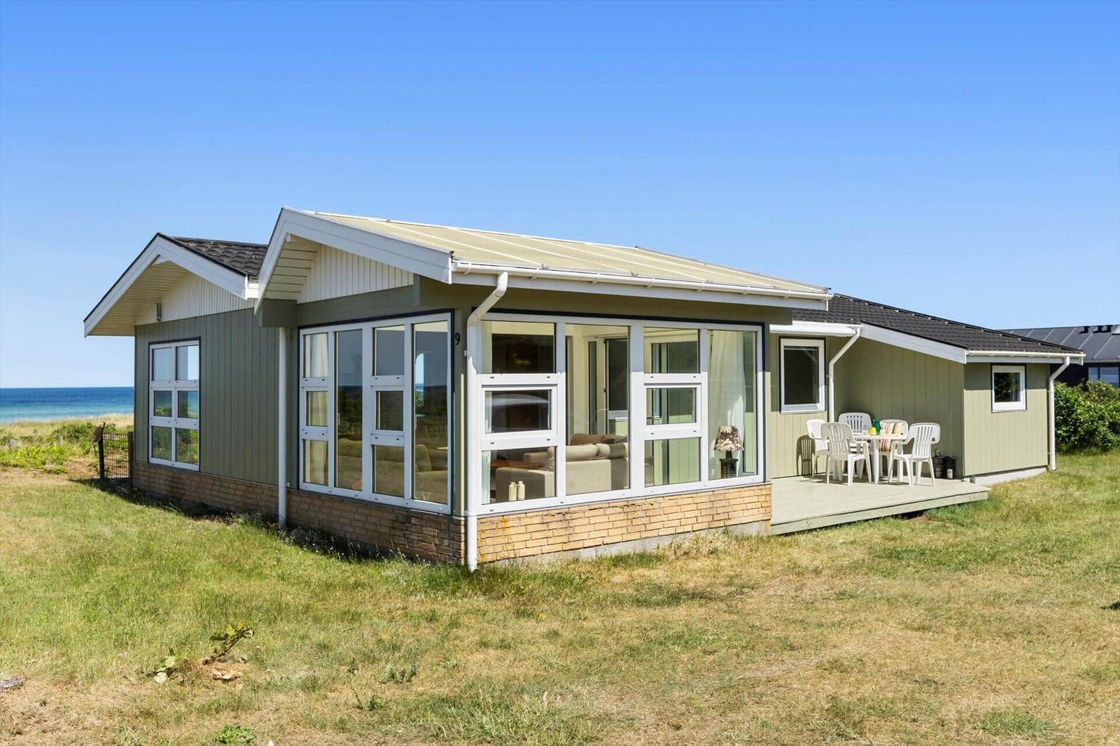 Moderne Strandvilla mit großem Fensterbereich und Terrasse. Blick auf das Meer.