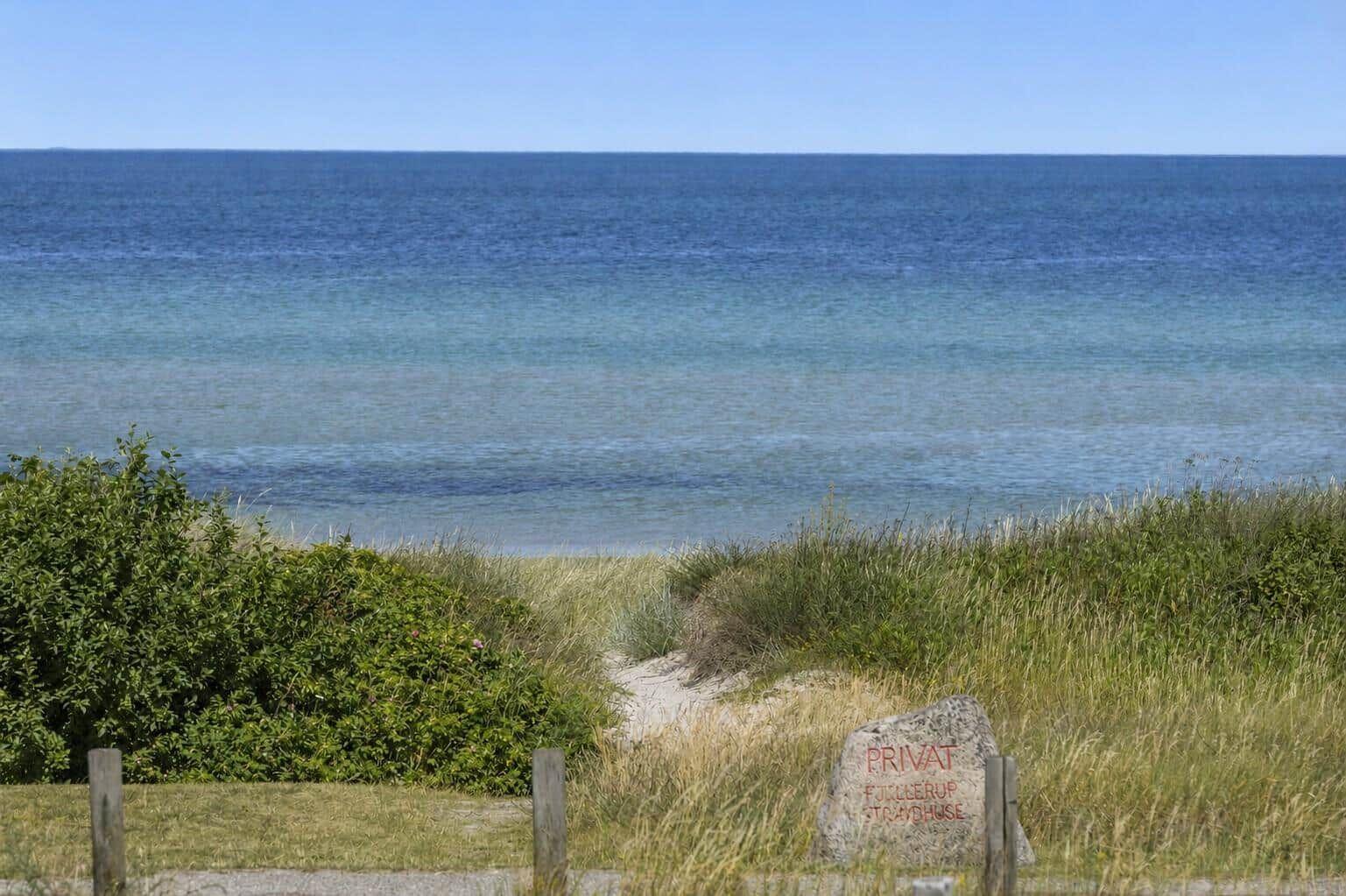 Privatstrandhaus mit Blick auf das Meer und grüne Dünen.
