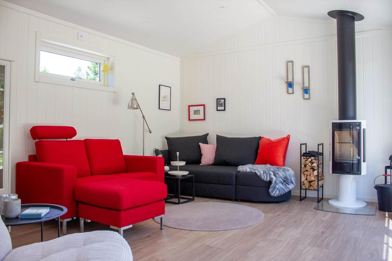 Ein Wohnzimmer mit rotem Sofa, schwarzem Sofa und Kaminofen.