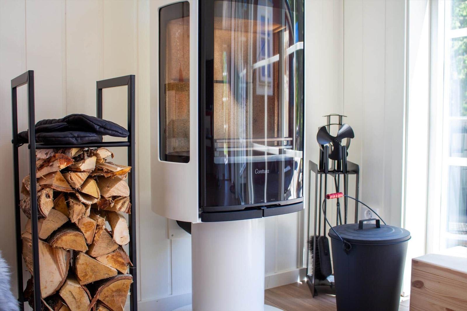 Moderne Kaminanlage mit Holzstapel und Feuerzeug im Raum.