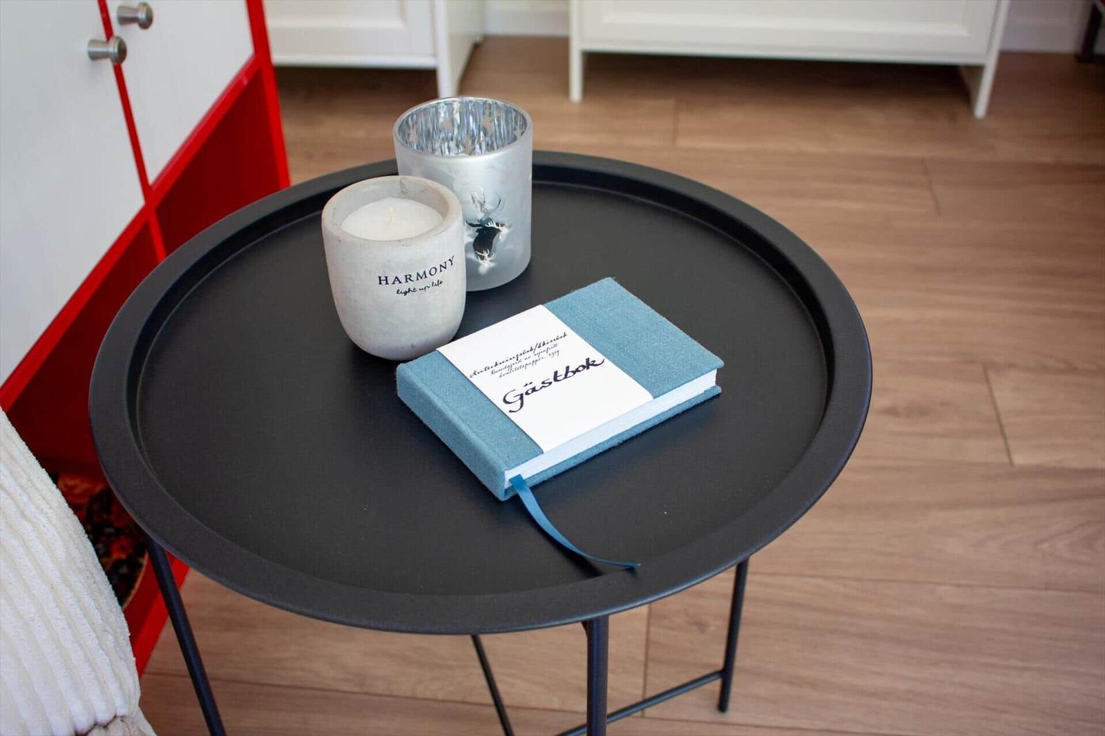 Runde Tisch mit Buch und zwei Kerzen auf Holzboden.