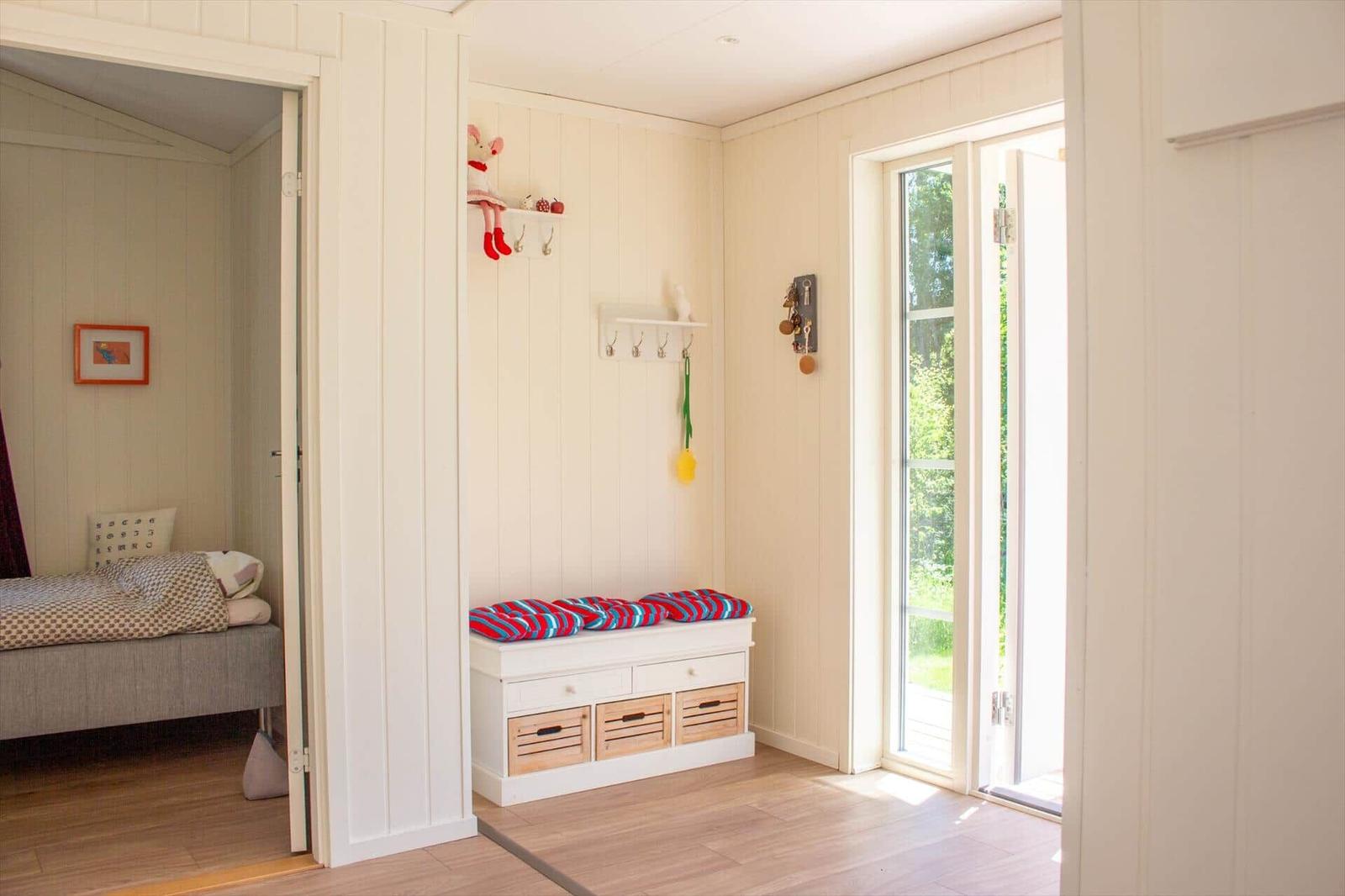 Eingangsbereich mit Sitzbank, Haken und Tür zum Schlafzimmer.