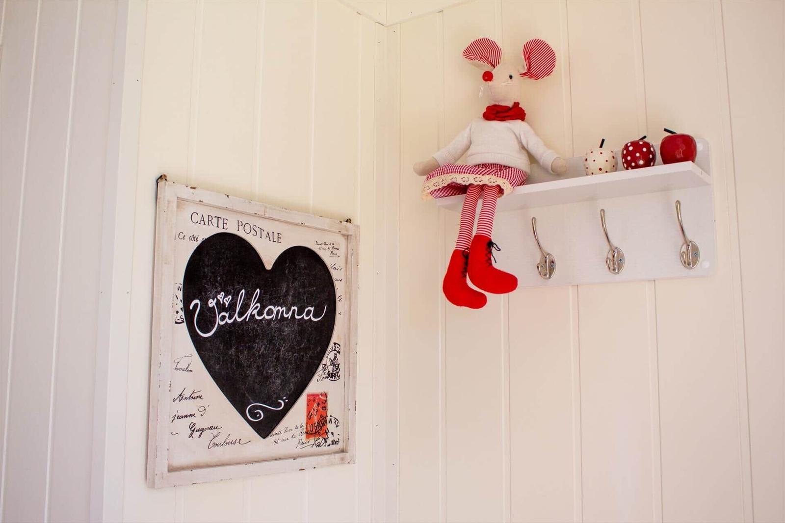 Wand mit Herz-Plakat und Stoffmaus auf Regal mit Haken.