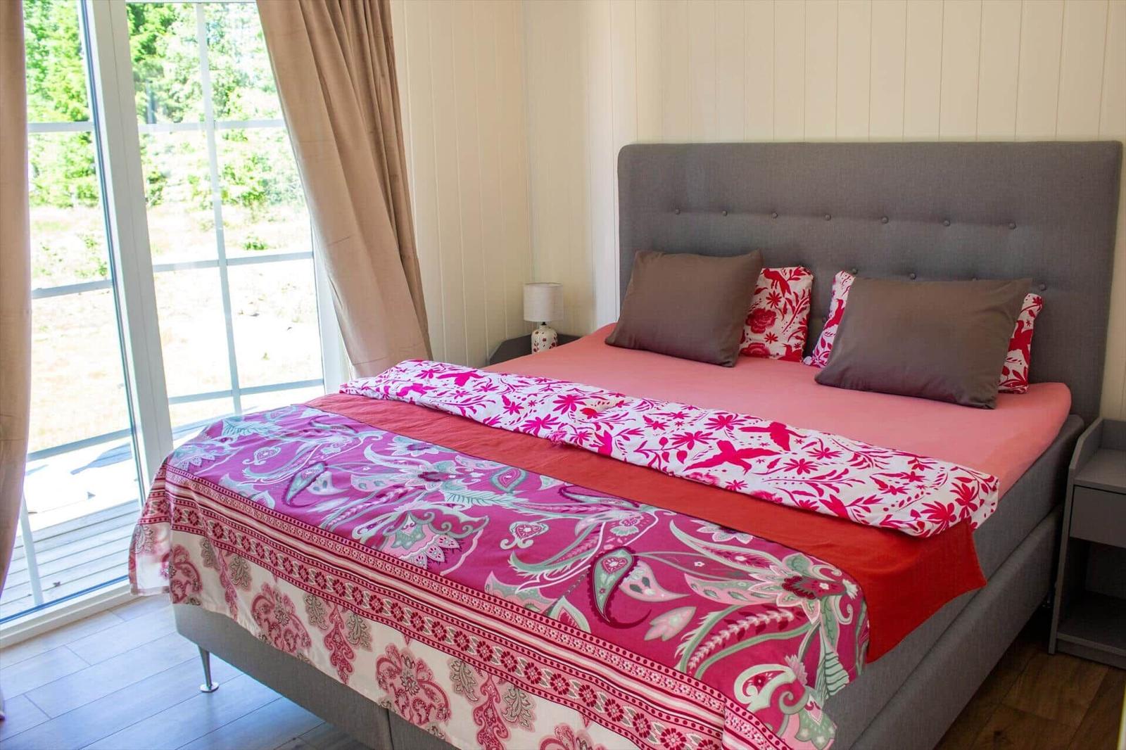Schlafzimmer mit Bett, Fenster und Vorhängen.