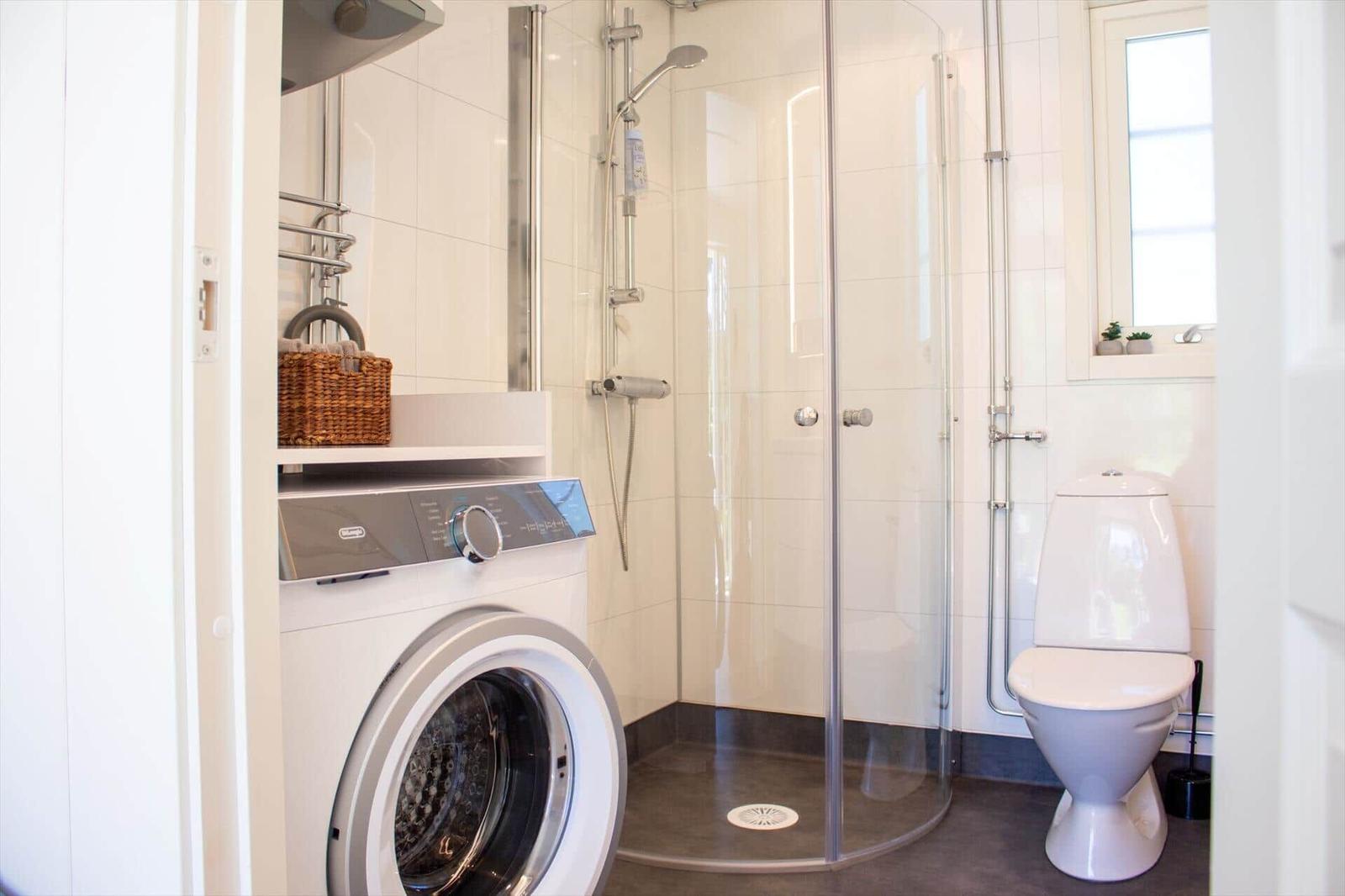 Badezimmer mit Dusche, Toilette und Waschmaschine.