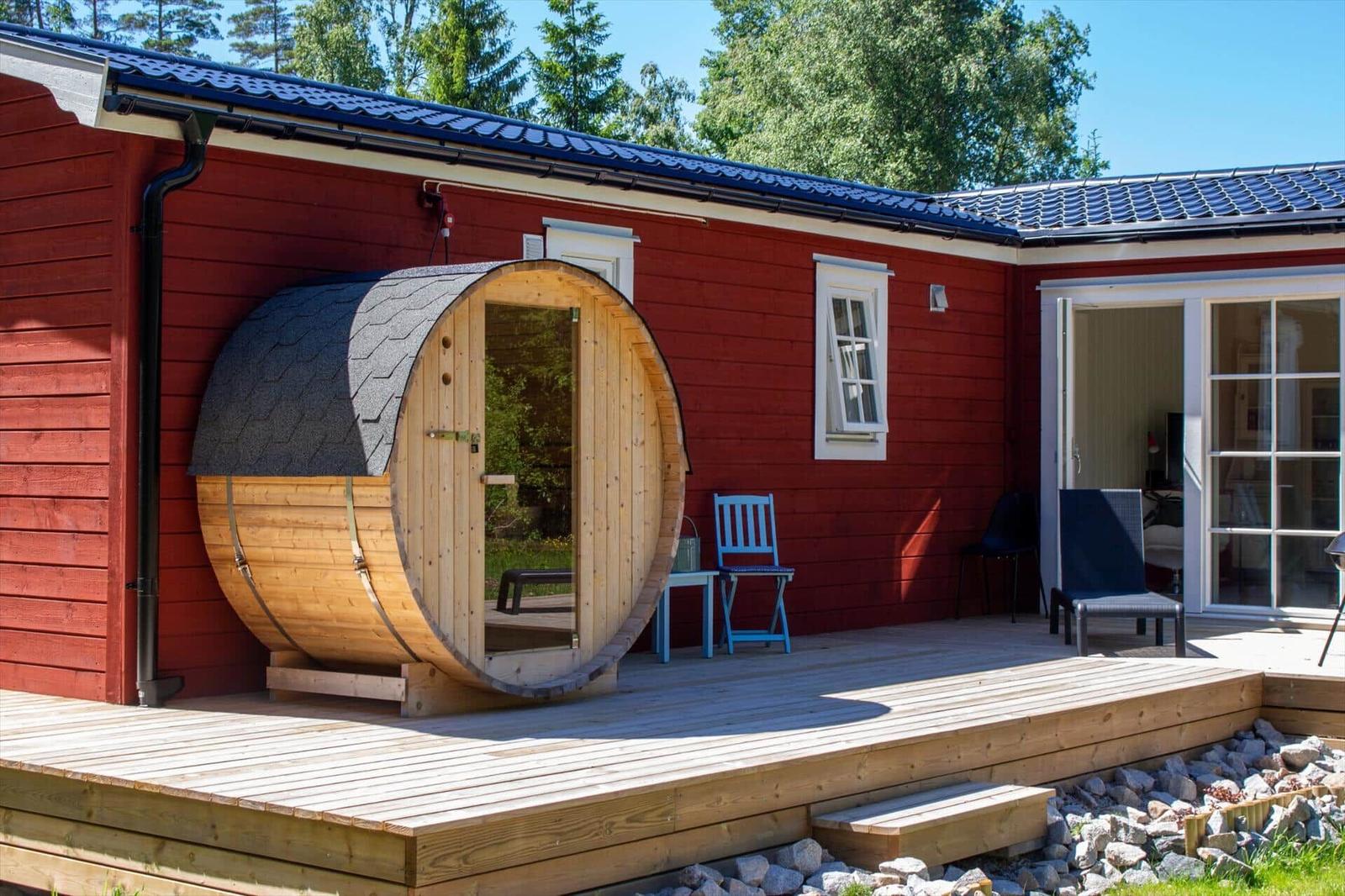 Roter Holzausbau mit Sauna aus Eiche und Terrasse mit Stühlen.