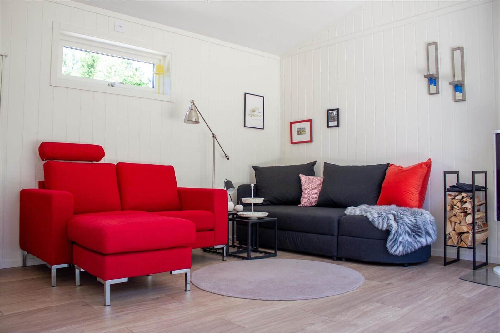 Ein Wohnzimmer mit rotem Sofa, schwarzem Sofa und Holzboden.