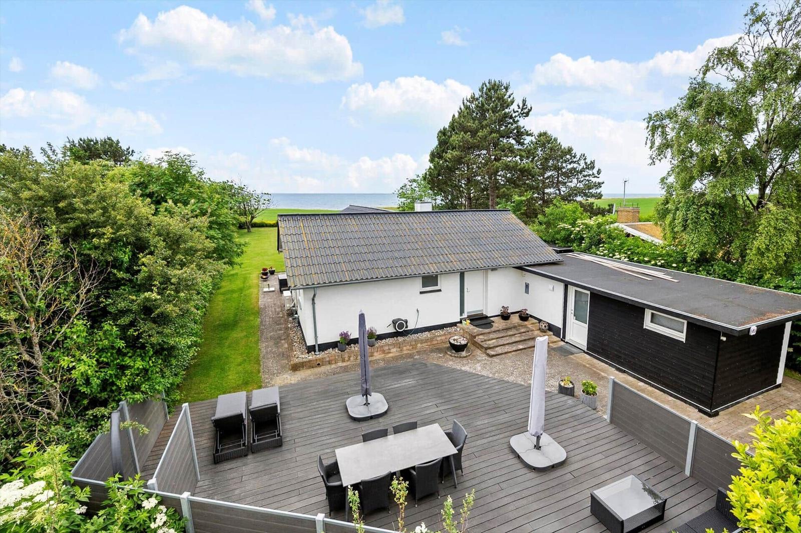 Haus mit Terrasse, Garten und Meerblick. Gartenmöbel und Sonnenschirme sind vorhanden.